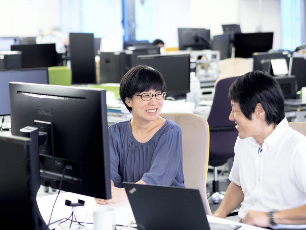 two employees in the office smiling at each other